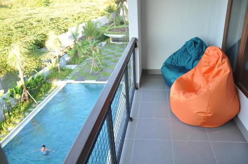 a balcony with a pool and a person in the water at Padang-Padang Inn in Uluwatu