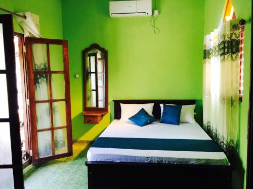 a bedroom with green walls and a bed with blue pillows at Galle Paradise Inn in Galle
