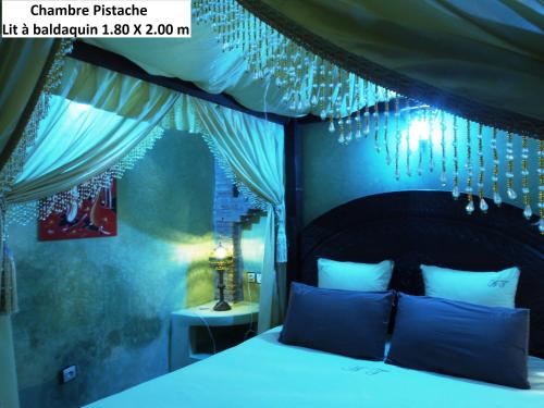 a bedroom with a bed with a canopy and chandeliers at Villa Grenadine in Essaouira
