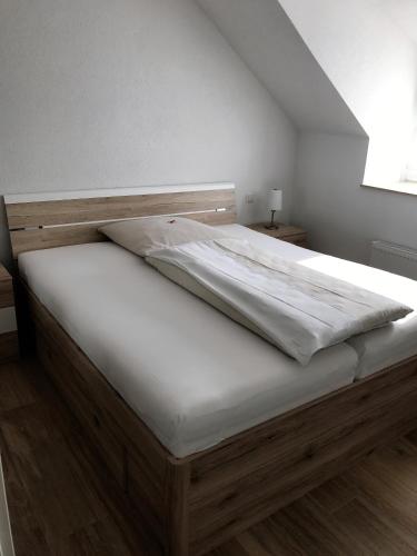 a bed with a wooden frame and white sheets at Ferienwohnungen Tannenhof in Steinen