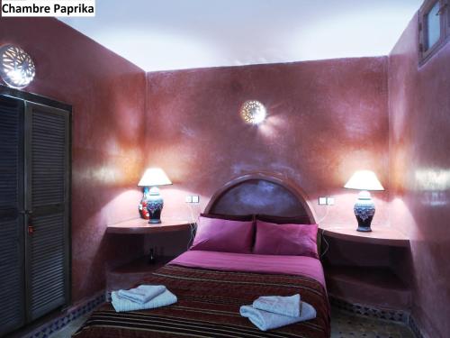 a bedroom with a bed with purple sheets and two lamps at Villa Grenadine in Essaouira