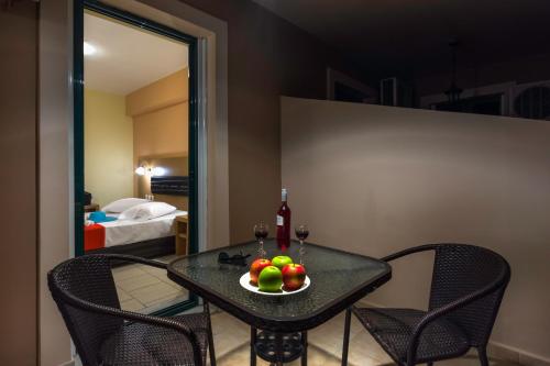 a table with a bowl of fruit and a bottle of wine at Kozanos Hotel & Suites in Amoudi