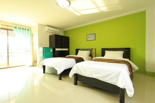 2 łóżka w pokoju z zielonymi ścianami w obiekcie See View Place w mieście Chiang Rai