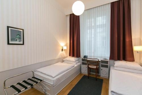 a hotel room with two beds and a television at Hotel Kärntnerhof in Vienna