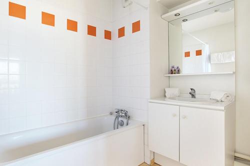 uma casa de banho branca com uma banheira e um lavatório em Neoresid - Résidence Le Valencey em Valence