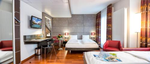 チューリッヒにあるホテル ステルネン エリコンのベッドとデスクが備わるホテルルームです。