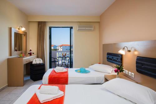 a hotel room with two beds and a balcony at Kozanos Hotel & Suites in Amoudi