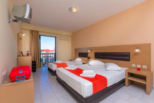 a hotel room with two beds and a red suitcase at Kozanos Hotel & Suites in Amoudi