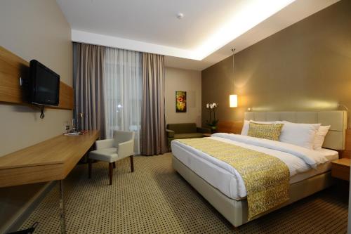 a hotel room with a large bed and a desk at Ramada by Wyndham Podgorica in Podgorica