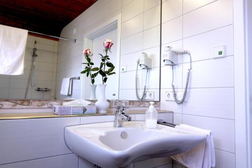 a white bathroom with a sink and a vase of roses at Gasthaus Seehof in Iznang