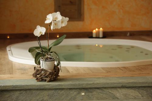 a vase with white flowers on a table next to a bath tub at La Luge D'Antan Maison d'Hôtes & SPA in Brusson
