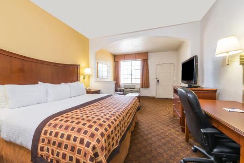 a hotel room with a bed and a desk and a computer at Americas Best Value Inn & Suites Fort Worth South in Fort Worth