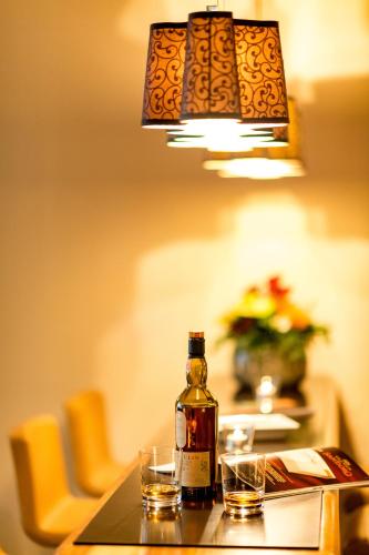 a bottle of whiskey sitting on a table with two glasses at Hotel Sternen Oerlikon in Zürich