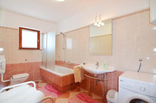 a bathroom with a sink and a tub and a toilet at Garden Apartment Maria in Vrsar