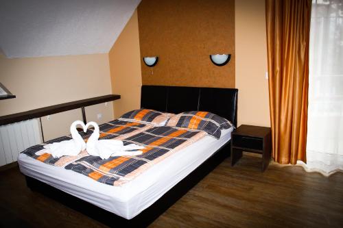 two white swans on a bed in a bedroom at Princess Apartman in Siófok