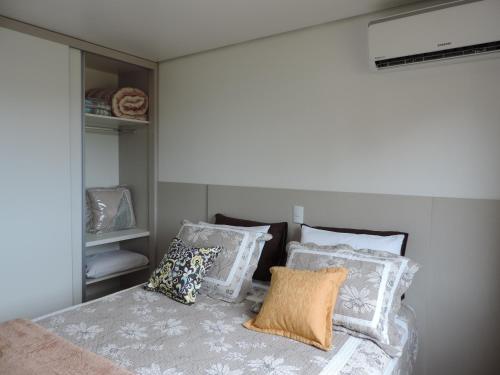 Un dormitorio con una cama con almohadas. en Canela - 2 suítes - Vivendas do Lago, en Canela