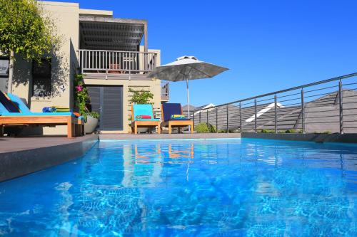 a swimming pool with an umbrella next to a house at Brenton Haven Beachfront Resort in Knysna