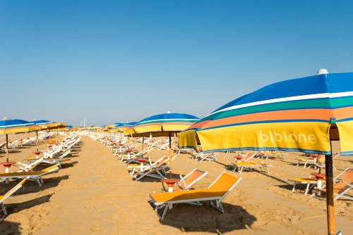 a bunch of chairs and umbrellas on a beach at Appartamenti Foyer in Bibione
