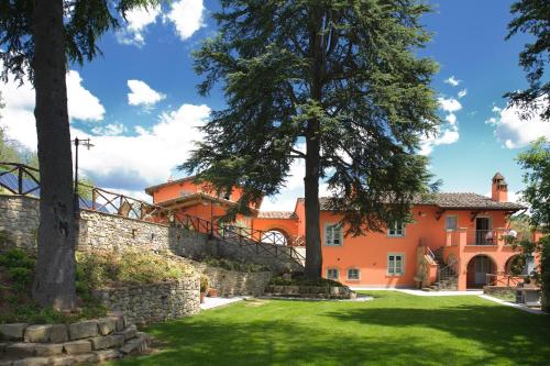 ein orangefarbenes Haus mit einer Steinmauer und Bäumen in der Unterkunft Agriturismo Villa Le Vigne in Montevarchi