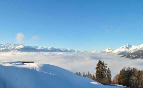 a view of a snow covered mountain with a layer of clouds at Les Petits Mélèzes in Crans-Montana