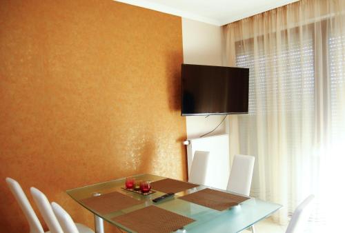 a dining room with a glass table and a television on the wall at Princess Luxus Apartman in Siófok