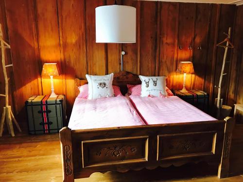 a bedroom with a bed with pink sheets and two lamps at Auberge de l'Assesseur - Mont-Soleil in Saint-Imier