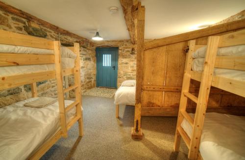 a bedroom with two bunk beds and a blue door at Widewath Barn in Penrith
