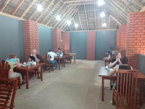 a group of people sitting at tables in a restaurant at Sigiriya Water Cottage in Sigiriya