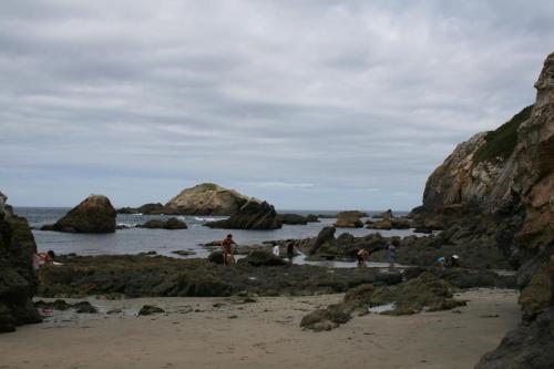 people on a beach with rocks in the water at Casa Tésera in El Franco