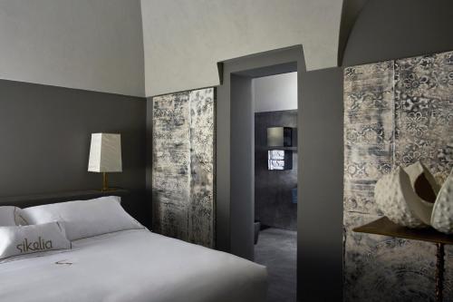 a bedroom with a large white bed and a doorway at Sikelia Luxury Hotel in Pantelleria