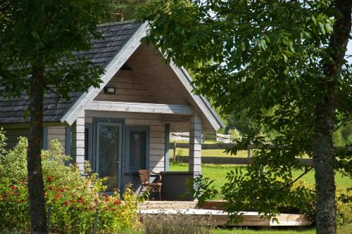 a small house with a porch and a chair at Niedras in Biksti