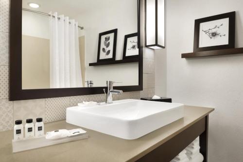 y baño con lavabo blanco y espejo. en Country Inn & Suites by Radisson, Houghton, MI, en Houghton