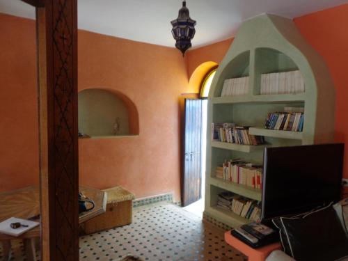 a room with orange walls and a book shelf with books at Villa Grenadine in Essaouira