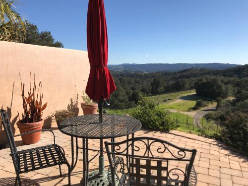 eine Terrasse mit einem Tisch, Stühlen und einem Sonnenschirm in der Unterkunft Dunning Vineyards Guest Villa in Paso Robles