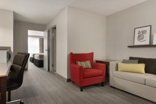 a living room with a red chair and a couch at Country Inn & Suites by Radisson, Houghton, MI in Houghton