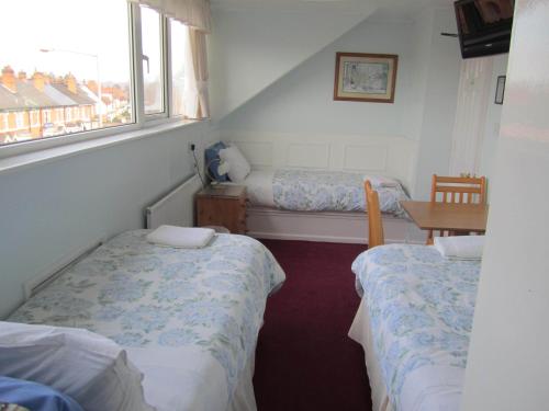 a small room with two beds and a table at Avoncot Guest House in Stratford-upon-Avon