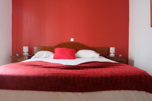 
a bed that has a red blanket on it at Hotel Alcides in Ponta Delgada
