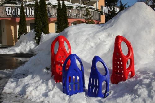 a pile of snow with blue and red plastic chairs in it at Waldschlössl in Latschach ober dem Faakersee