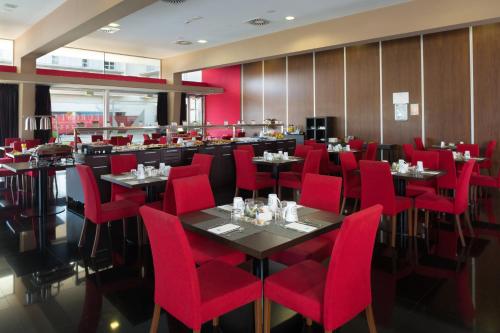 a dining room with red chairs and tables at Eurostars Rey Fernando in Zaragoza