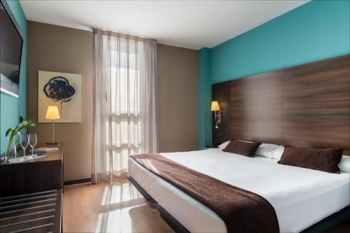 a bedroom with a large bed and a blue wall at Eurostars Rey Fernando in Zaragoza