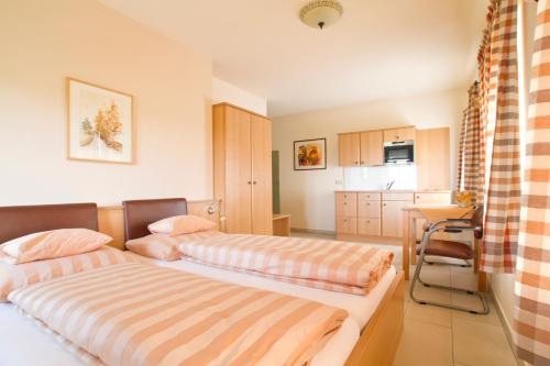 a bedroom with two beds and a desk and a kitchen at Frühstückspension Herzog zu Laah in Linz