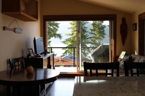a living room with a table and a large window at Tilby's Rainbow Cottage in Port Renfrew