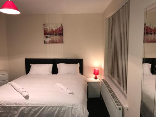 una camera da letto con un letto con lenzuola bianche e una lampada rossa di Victoria Parade Apartment a Hull