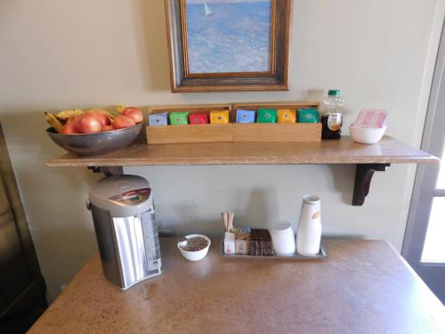a counter with a shelf with a bowl of apples and a coffee maker at Brentwood Inn in Los Angeles