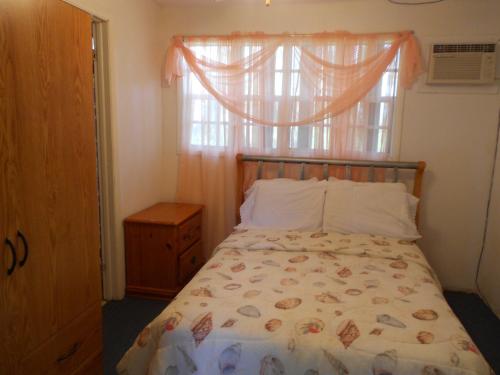 a bedroom with a bed with a window and a dresser at Nathan's Lodge in Kemps Bay