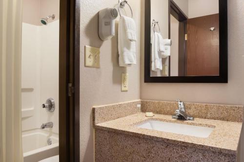 a bathroom with a sink and a mirror and a tub at Super 8 by Wyndham Rantoul in Rantoul