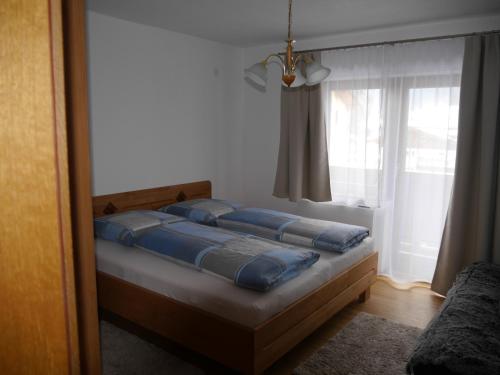 Un dormitorio con una cama con almohadas azules y una ventana en Ferienwohnung Enn, en Neukirchen am Großvenediger