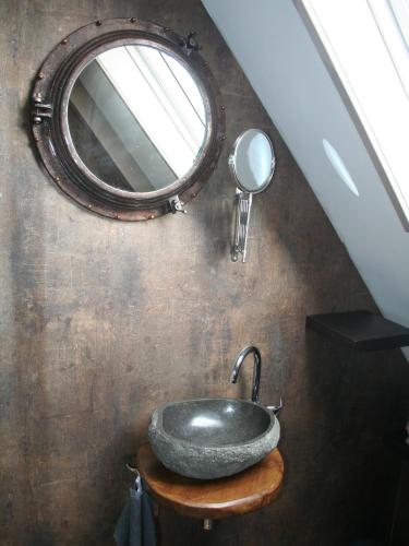a bathroom with a stone sink and a mirror at Het Huis van de Wadden in Den Oever