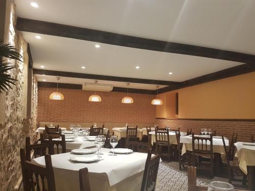 une salle à manger avec des tables, des chaises et un tissu de table blanc dans l'établissement Hostal Mesón Castilla, à Sigüenza