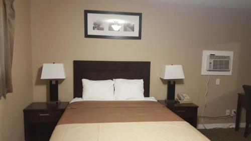 a hotel room with a bed with two lamps at Sunrise Motel in Regina